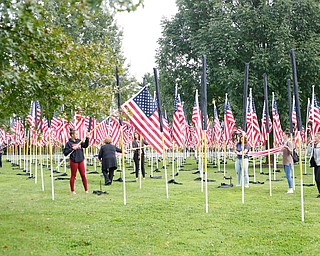 Volunteers help take down, roll, and bag the flags after the closing ceremonies for the traveling memorial on Sunday. EMILY MATTHEWS | THE VINDICATOR