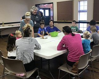 Neighbors | Jessica Harker.Children gathered at the An Apple a Day event at MillCreek Metroparks Farms colored pictures before listening to Naturalist Brenda Marley (back) read a story.