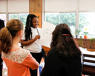 Sherri Wright, a sophomore at Youngstown Rayen Early College High School, shows her tour group one of her art projects during a tour of the new Youngstown Rayen Early College High School on Thursday.