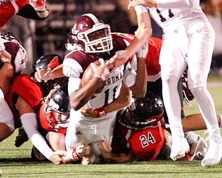 Boardman's Che Trevena holds onto the ball as he gets tackled by Canfield during the first half of their game at Canfield on Friday. EMILY MATTHEWS | THE VINDICATOR