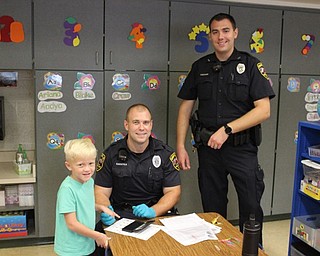 Neighbors | Abby Slanker.Canfield Police Department School Resource Officer Steve Garstka (sitting) and School Resource Officer Tim Lamping fingerprinted a C.H. Campbell Elementary School kindergartner for the Child Safety Fingerprint ID Kits the department provided for kindergartners on Sept. 18.