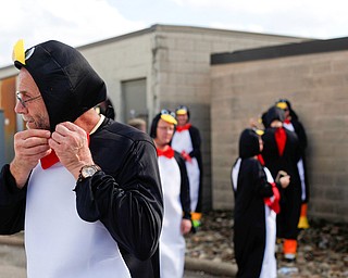 Jerry Fleming, of Columbiana, puts on his penguin costume  with other penguins before the YSU homecoming parade on Saturday. EMILY MATTHEWS | THE VINDICATOR