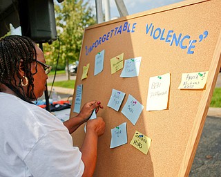 Rose Wilkins, of Youngstown, puts the names of people she knew who lost their lives to violence on the "Unforgettable Violence" board with other names during the Nonviolence Week Rally outside of Covelli Centre on Sunday afternoon. EMILY MATTHEWS | THE VINDICATOR