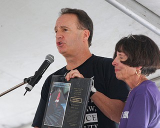 Jeff Steinberg, the Founder and Executive Director of Sojourn to the Past, gives a plaque to Penny Wells, the director of the Mahoning Valley chapter of Sojourn, at the Nonviolence Week Rally outside of Covelli Centre on Sunday afternoon. EMILY MATTHEWS | THE VINDICATOR