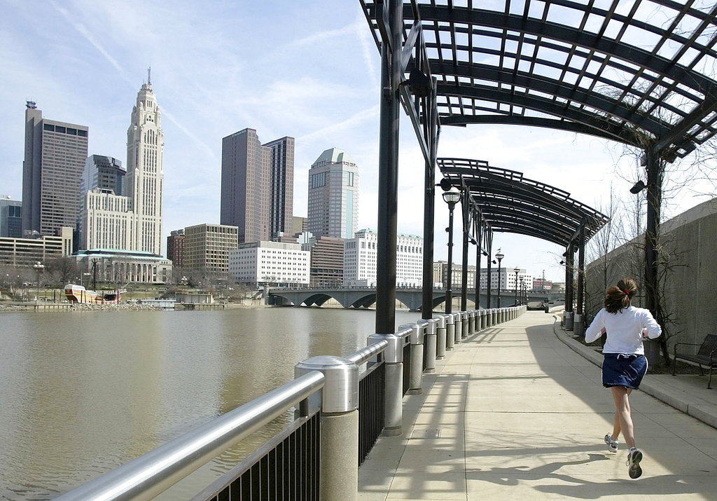 In this March 15, 2004, file photo, a woman runs the Franklinton floodwall next to the Scioto River in Columbus, Ohio. The largest city named for Christopher Columbus has called off its observance of the holiday named for the explorer. Offices in Columbus will remain open Monday, Oct. 8, 2018, and close on Veterans Day instead.