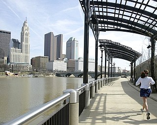 In this March 15, 2004, file photo, a woman runs the Franklinton floodwall next to the Scioto River in Columbus, Ohio. The largest city named for Christopher Columbus has called off its observance of the holiday named for the explorer. Offices in Columbus will remain open Monday, Oct. 8, 2018, and close on Veterans Day instead.