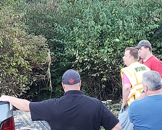 Local officials assess an unknown substance found Monday in a stream being Canfield High School, as they await arrival of Ohio EPA officials.