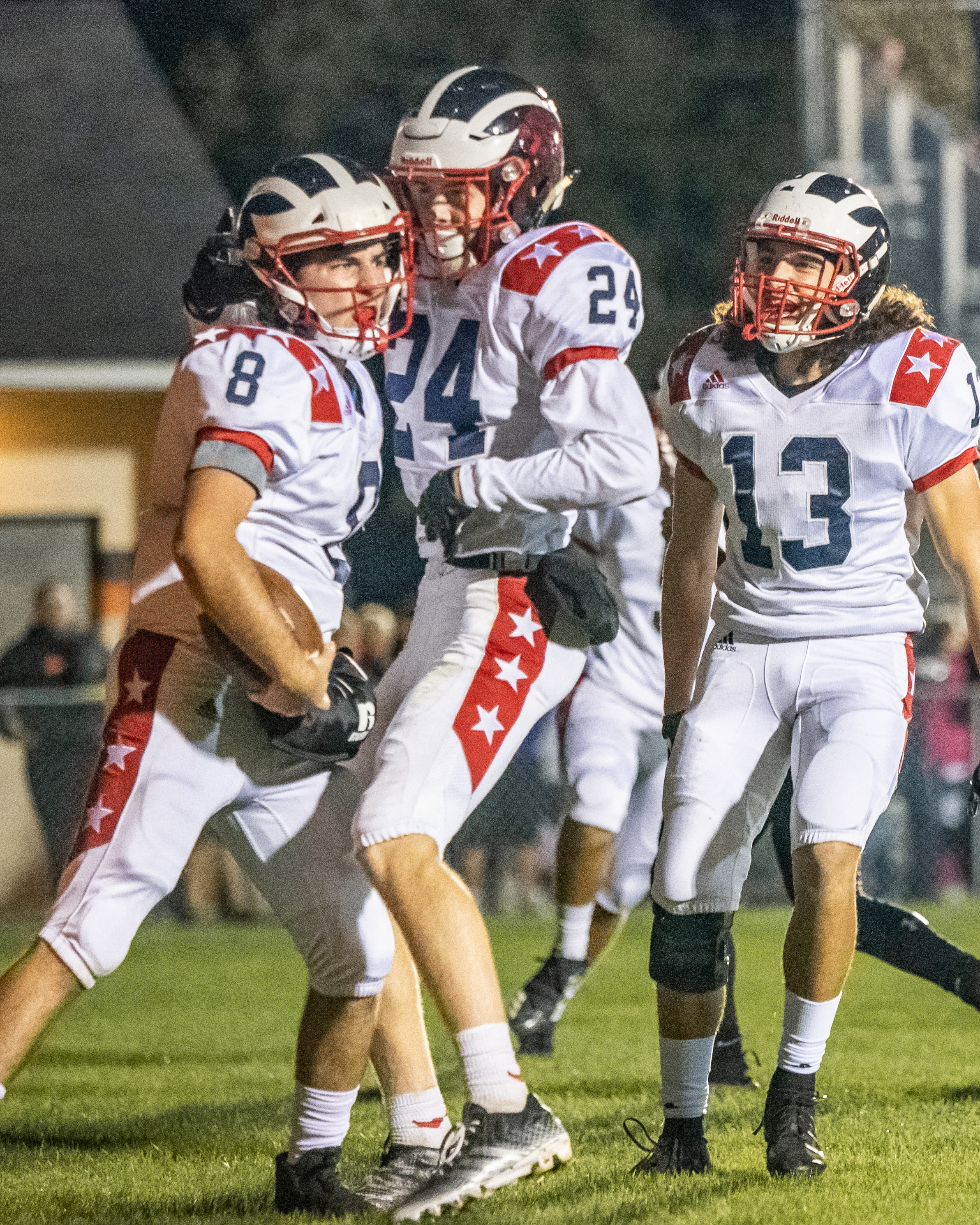 Zack Leonard (8), of Niles McKinley High School, is congratulated by teammates Chase Sudzina (24) and Jason Gibson (13) after scoring a touchdown Thursday night in the Red Dragons victory over Howland High School's Tigers at Lombardo Field