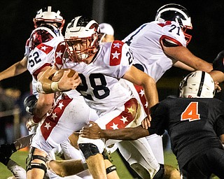 DIANNA OATRIDGE | THE VINDICATOR Niles' running back Robbie Savin (28) powers through a hole, eluding the grasp of Howland's Cartier Yancy (4) during their game at Lombardo Field on Thursday.