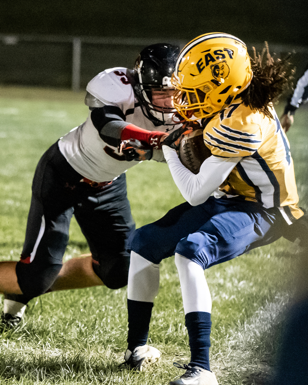 DIANNA OATRIDGE | THE VINDICATOR Canfield linebacker Carter Myers (33) pushes Youngstown East's DeRon Gilbert (17) out of bounds during their game at Rayen Stadium in Youngstown on Friday.