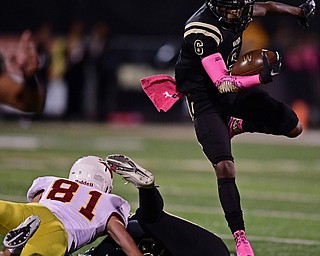 WARREN, OHIO - OCTOBER 12, 2018: Harding's Chris Chew hurdles over teammate Isaiah Caysonwho was blocking Mooney's Anthony Fire during the first half of their game, Friday night at Warren Harding High School. DAVID DERMER | THE VINDICATOR