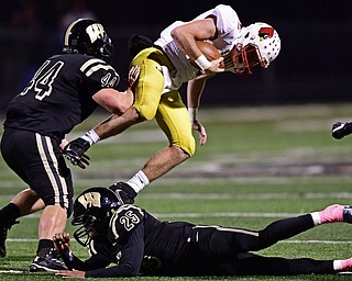 WARREN, OHIO - OCTOBER 12, 2018: Mooney's John Murphy, top, flies through the air after being hit by Harding's Jared Zillinger, left, and Ty Artis during the first half of their game, Friday night at Warren Harding High School. DAVID DERMER | THE VINDICATOR