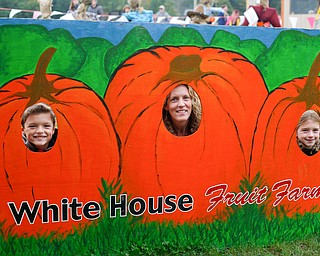 From left, Hayden Six, 9, Nikki Six, and Kendall Six, 9, all of Chester, West Virginia, pose in a pumpkin sign at White House Fruit Farm on Saturday. EMILY MATTHEWS | THE VINDICATOR