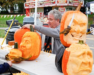 Ron Roberts, of Salem, carves a pumpkin while others he has carved are on display at White House Fruit Farm on Saturday. Roberts said this is his fourth year carving pumpkins for display at White House Fruit Farm. EMILY MATTHEWS | THE VINDICATOR
