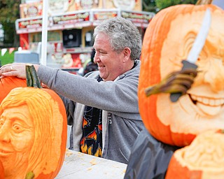 Ron Roberts, of Salem, carves a pumpkin while others he has carved are on display at White House Fruit Farm on Saturday. Roberts said this is his fourth year carving pumpkins for display at White House Fruit Farm. EMILY MATTHEWS | THE VINDICATOR