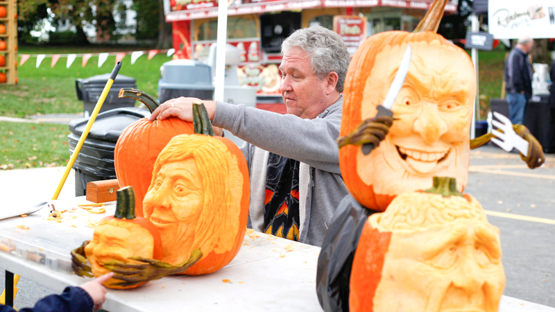 Ron Roberts, of Salem, carves a pumpkin while others he has carved are on display at the annual Fall Festival at White House Fruit Farm, 9249 Youngstown-Salem Road, Canfield.
