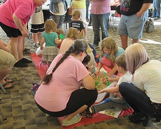 Neighbors | Jessica Harker.Groups of children assisted by their parents dug through sand for hidden items at one of the many stations set up during the "Paw Patrol" party at the Austintown library.