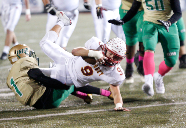 Cardinal Mooney's Jason Santisi holds onto the ball as he gets tackled by Ursuline's Daysean Harris during the first half of their game at Stambaugh Studium on Friday. EMILY MATTHEWS | THE VINDICATOR