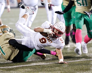 Cardinal Mooney's Jason Santisi holds onto the ball as he gets tackled by Ursuline's Daysean Harris during the first half of their game at Stambaugh Studium on Friday. EMILY MATTHEWS | THE VINDICATOR