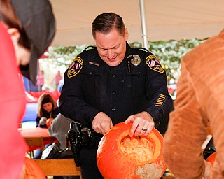 Canfield police officer Mike Sroka carves a pumpkin at the Canfield Police Department's Fall Festival on Saturday. EMILY MATTHEWS | THE VINDICATOR