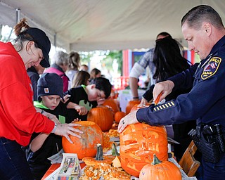 Canfield police officer Mike Sroka, right, carves a pumpkin with others at the Canfield Police Department's Fall Festival on Saturday. EMILY MATTHEWS | THE VINDICATOR