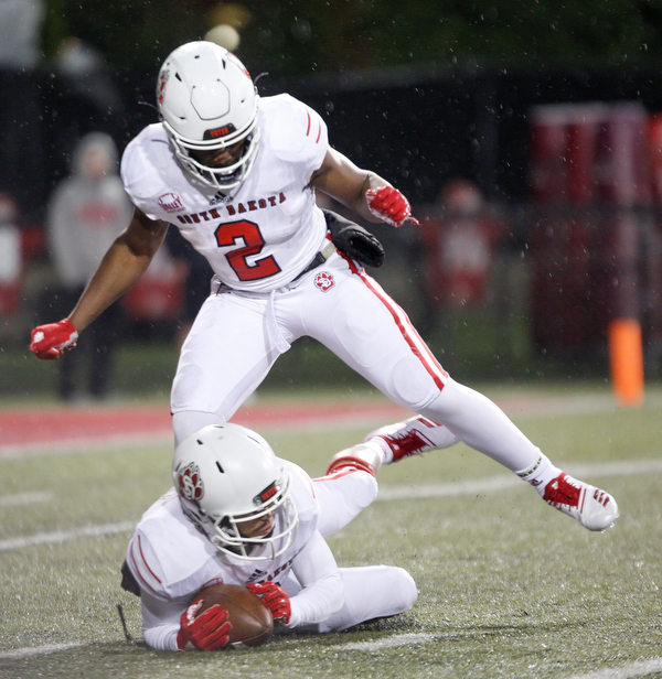 South Dakota's Kai Henry, above, steps over Trystn Ducker as Ducker grabs the ball during the first half of their game against Youngstown State at Stambaugh Stadium on Saturday. EMILY MATTHEWS | THE VINDICATOR