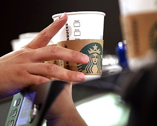 In this May 29, 2018, file photo, a barista reaches for an empty cup at a Starbucks in the Pike Place Market in Seattle. Starbucks has opened its first U.S. “signing store” to better serve hard of hearing customers. The store in Washington, D.C. is just blocks from Galludet Univerisity, one of the nation’s oldest universities serving deaf and hard-of-hearing students.