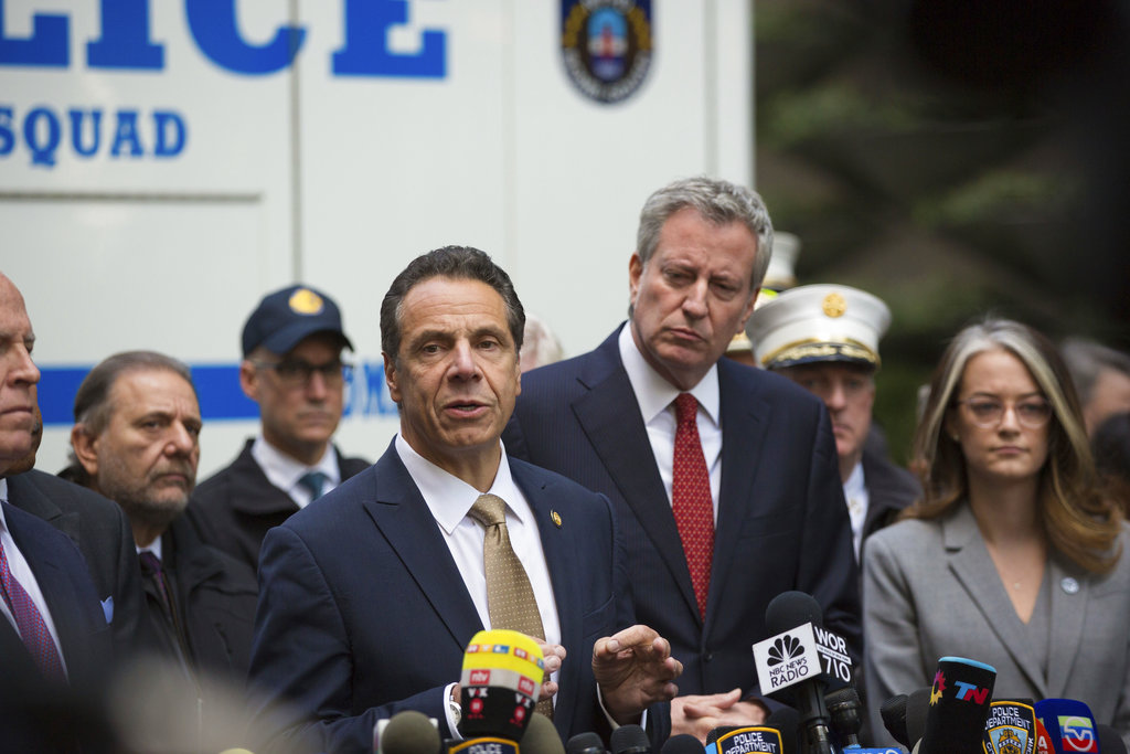 Mayor Bill de Blasio looks on as Gov. Andrew Cuomo delivers remarks during a news conference after NYPD personnel removed an explosive device from Time Warner Center on Wednesday, Oct. 24, 2018, in New York. The U.S. Secret Service says agents have intercepted packages containing "possible explosive devices" addressed to former President Barack Obama and Hillary Clinton.