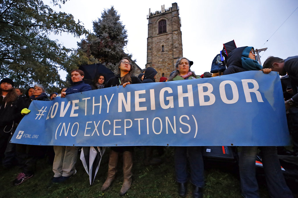 A group holds a sign at the intersection of Murray and Forbes avenues in the Squirrel Hill section of Pittsburgh during a memorial vigil for the victims of the shooting at the Tree of Life Synagogue where a shooter opened fire, killing multiple people and wounding others, including several police officers, Saturday, Oct. 27, 2018.