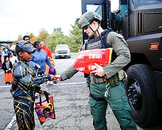 Mylan Martin, left, 9, of Youngstown, dressed as Erik Killmonger from the movie Black Panther, gets candy from  Bryan Brooks, a member of the Violent Crimes Task Force, during the trick-or-treat event at Covelli Centre on Tuesday. EMILY MATTHEWS | THE VINDICATOR
