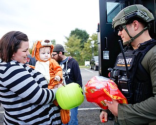 Amanda Ritt, left, of Girard, holds her son Braden Hamerik, 1, dressed as a kangaroo, as he gets candy from  Bryan Brooks, a member of the Violent Crimes Task Force, during the trick-or-treat event at Covelli Centre on Tuesday. EMILY MATTHEWS | THE VINDICATOR
