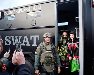 Amelia Schall, 8, dressed as a witch, and Coltin Schall, 10, dressed as a ghoul, both of Warren, pose for a photo inside the SWAT van with Deputy Jeff Duzzny during the trick-or-treat event at Covelli Centre on Tuesday. EMILY MATTHEWS | THE VINDICATOR