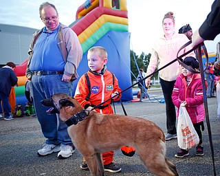 James Barber, 4, of Youngstown, dressed as a flight commander for NASA, pets Mercy, a nine-year-old Belgian Malinois police dog, while his dad Andrew Barber, left, stands by during the trick or treat event at Covelli Centre on Tuesday. Mercy will be retiring from duty at the end of November. EMILY MATTHEWS | THE VINDICATOR