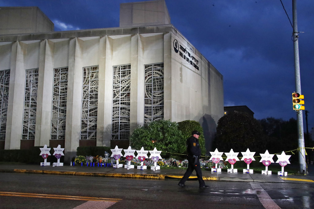 In this Oct. 28, 2018, file photo a Pittsburgh police officer walks past the Tree of Life Synagogue and a memorial of flowers and stars in Pittsburgh in remembrance of those killed and injured when a shooter opened fire during services Saturday at the synagogue. The perpetrators of mass shootings often provide a treasure trove of insight into their violent tendencies on social media. But the information is not always seen by law enforcement until after the violence is carried out.
