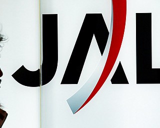 In this file photo dated Friday, Jan. 8, 2010, a passenger walks past the Japan Airlines (JAL) logo at Haneda Airport in Tokyo, Japan. Japan Airlines co-pilot Katsutoshi Jitsukawa was arrested Sunday after failing a breath test shortly before a London to Tokyo flight and pleaded guilty in court Thursday Nov. 1, 2018, to being almost 10 times over the legal limit for alcohol.
