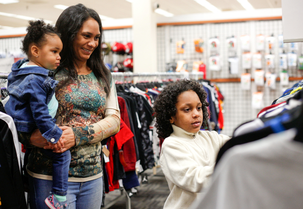 Landen Fitzgerald-Green, 8, looks at shirts with his mom Lisa Fitzgerald-Green and sister Herlo Fitzgerald-Green, 16 months, in the Burlington store in Boardman during a shopping spree his family received to celebrate his recovery from Leukemia on Thursday. EMILY MATTHEWS | THE VINDICATOR
