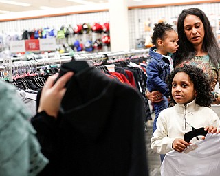 Landen Fitzgerald-Green, 8, looks at a shirt that Lindsay Silverstein, the Executive Director of the Leukemia and Lymphoma Society, is holding up while his mom Lisa Fitzgerald-Green and sister Herlo Fitzgerald-Green, 16 months, stand behind him in the Burlington store in Boardman during a shopping spree his family received to celebrate his recovery from Leukemia on Thursday. EMILY MATTHEWS | THE VINDICATOR