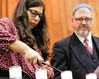 Laura Silverman lights a candle for Richard Gottfried, a victim at the Tree of Life Synagogue, with help from Rabbi Schonberger, during an interfaith vigil for the Pittsburgh Tree of Life Synagogue victims at Temple El Emeth in Liberty on Thursday evening. EMILY MATTHEWS | THE VINDICATOR