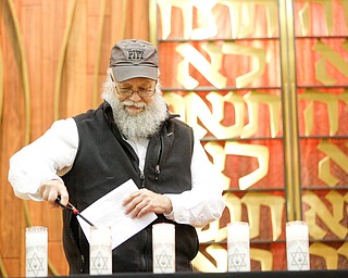 Alvin Weisberg, of Squirrel Hill, lights a candle for Melvin Wax, one of the victims of the shooting at the Tree of Life Synagogue, during an interfaith vigil for the Pittsburgh Tree of Life Synagogue victims at Temple El Emeth in Liberty on Thursday evening. EMILY MATTHEWS | THE VINDICATOR