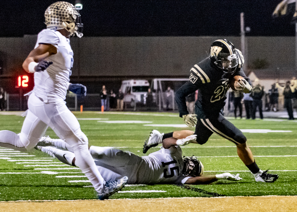 DIANNA OATRIDGE | THE VINDICATOR  Warren Harding's Elijah Smith (27) eludes the grasp of Garfield Heights' Donald Willis (15) and the pursuit of Javion Binns (8) on his way to the end zone in the first quarter of their first round playoff game against Garfield Heights at Mollenkopf Stadium in Warren on Friday.