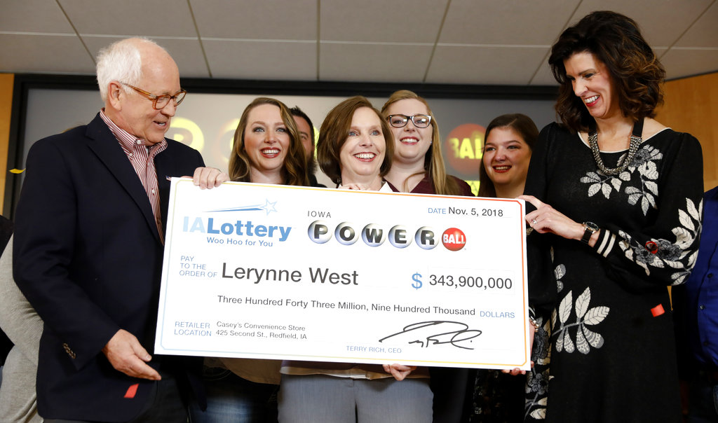 Iowa Lottery CEO Terry Rich, left, presents a check to Lerynne West, of Redfield, Iowa, center, for her share of a nearly $700 million Powerball prize, Monday, Nov. 5, 2018, at the Iowa Lottery headquarters in Clive, Iowa. West was one of two winners of a $688 million jackpot drawn Oct. 27. She'll share the prize with someone who bought the other winning ticket in New York City.