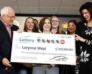 Iowa Lottery CEO Terry Rich, left, presents a check to Lerynne West, of Redfield, Iowa, center, for her share of a nearly $700 million Powerball prize, Monday, Nov. 5, 2018, at the Iowa Lottery headquarters in Clive, Iowa. West was one of two winners of a $688 million jackpot drawn Oct. 27. She'll share the prize with someone who bought the other winning ticket in New York City.
