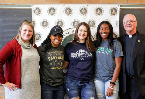 From left, Ursuline High School Assistant Principal Maggie Matune, senior basketball players Dayshanette Harris, Lindsay Bell, Anyah Curd, and President Father Richard Murphy pose for a photo during the signing day ceremony at Ursuline High School on Wednesday. EMILY MATTHEWS | THE VINDICATOR