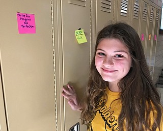 Neighbors | Jessica Harker.Bella Beight, a member of the Kindness Club at Poland Middle School, posted sticky notes on the lockers of the school.