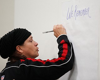 Joann Jones, of the East Side, writes the names of people she knew who have died from violence at a community meeting at St. Dominic Church on Thursday night. EMILY MATTHEWS | THE VINDICATOR