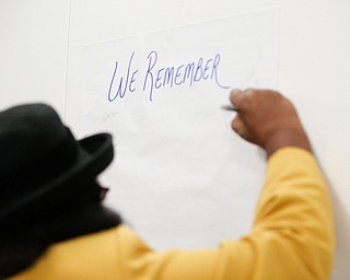 Anita Davis, councilwoman of the 6th Ward, writes the names of three of her family members who have died from violence at a community meeting at St. Dominic Church on Thursday night. EMILY MATTHEWS | THE VINDICATOR