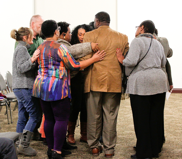 Community leaders and members hug relatives of Valarica Blair and her 3-month-old son Tariq Morris, who were killed in a triple homicide last week, during a community meeting at St. Dominic Church on Thursday night. EMILY MATTHEWS | THE VINDICATOR