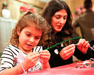 Aria Ries, 5, of Niles, puts beads onto a pipe cleaner to make a Christmas ornament with her mom Gina Ries at the Memories of Christmas Past exhibition at The Arms Family Museum on Saturday. EMILY MATTHEWS | THE VINDICATOR