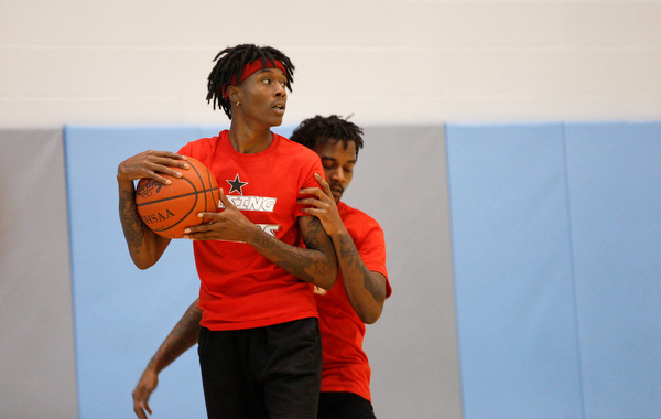 Local artist JonezyTooCool takes control of the ball while Craig Jackson, who is in the music group Steez Paradise with JonezyTooCool, runs up behind him during the Rising Stars basketball game at East High School on Sunday. EMILY MATTHEWS | THE VINDICATOR