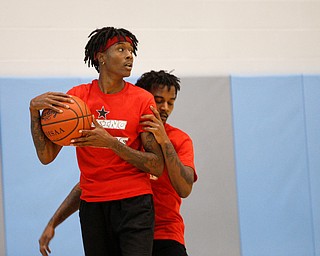 Local artist JonezyTooCool takes control of the ball while Craig Jackson, who is in the music group Steez Paradise with JonezyTooCool, runs up behind him during the Rising Stars basketball game at East High School on Sunday. EMILY MATTHEWS | THE VINDICATOR